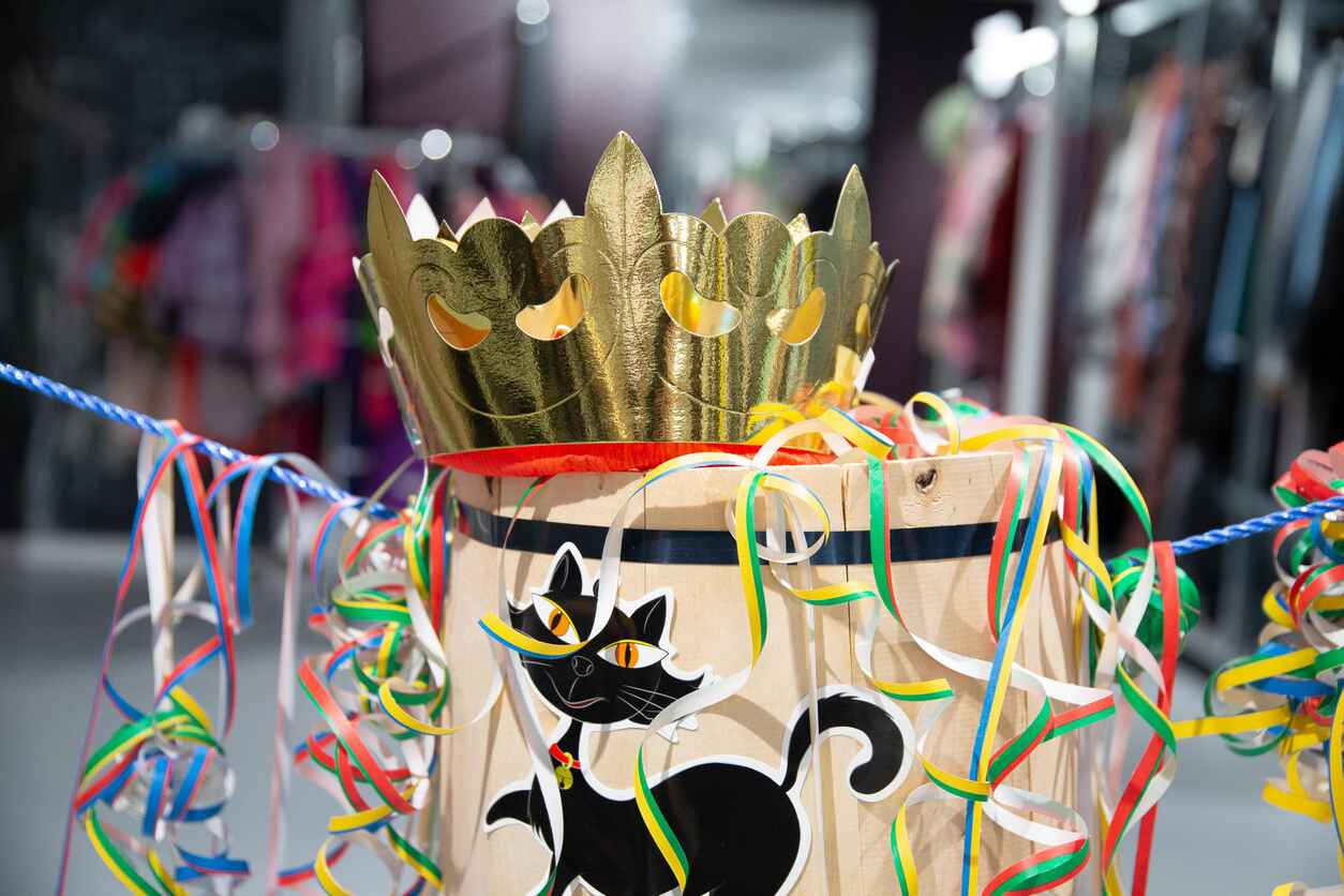 A traditional Fastelavn barrel, adorned with colorful ribbons, a black cat illustration, and a golden crown, representing the festive Danish carnival game.