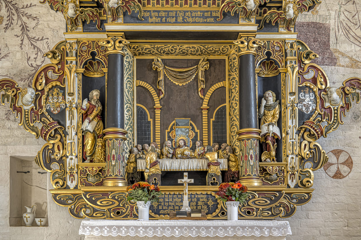 An ornate altarpiece in Elmelunde Church, Denmark, depicting the Last Supper and religious figures, symbolizing the significance of Maundy Thursday.