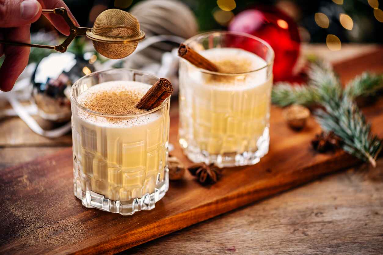 Two festive glasses of spiced holiday eggnog, garnished with cinnamon, capturing the cozy spirit of Christmas celebrations.
