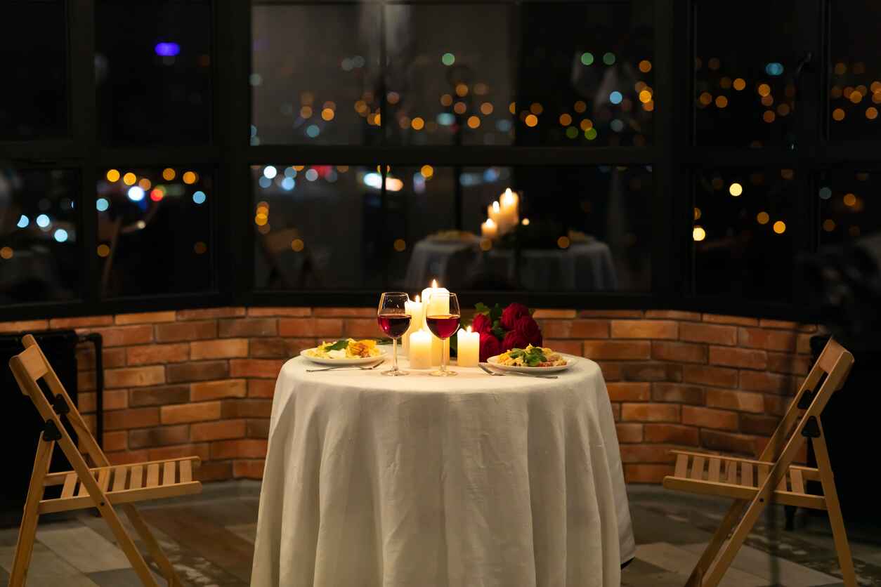 A beautifully set table with candlelight, red wine, and a romantic dinner for two.