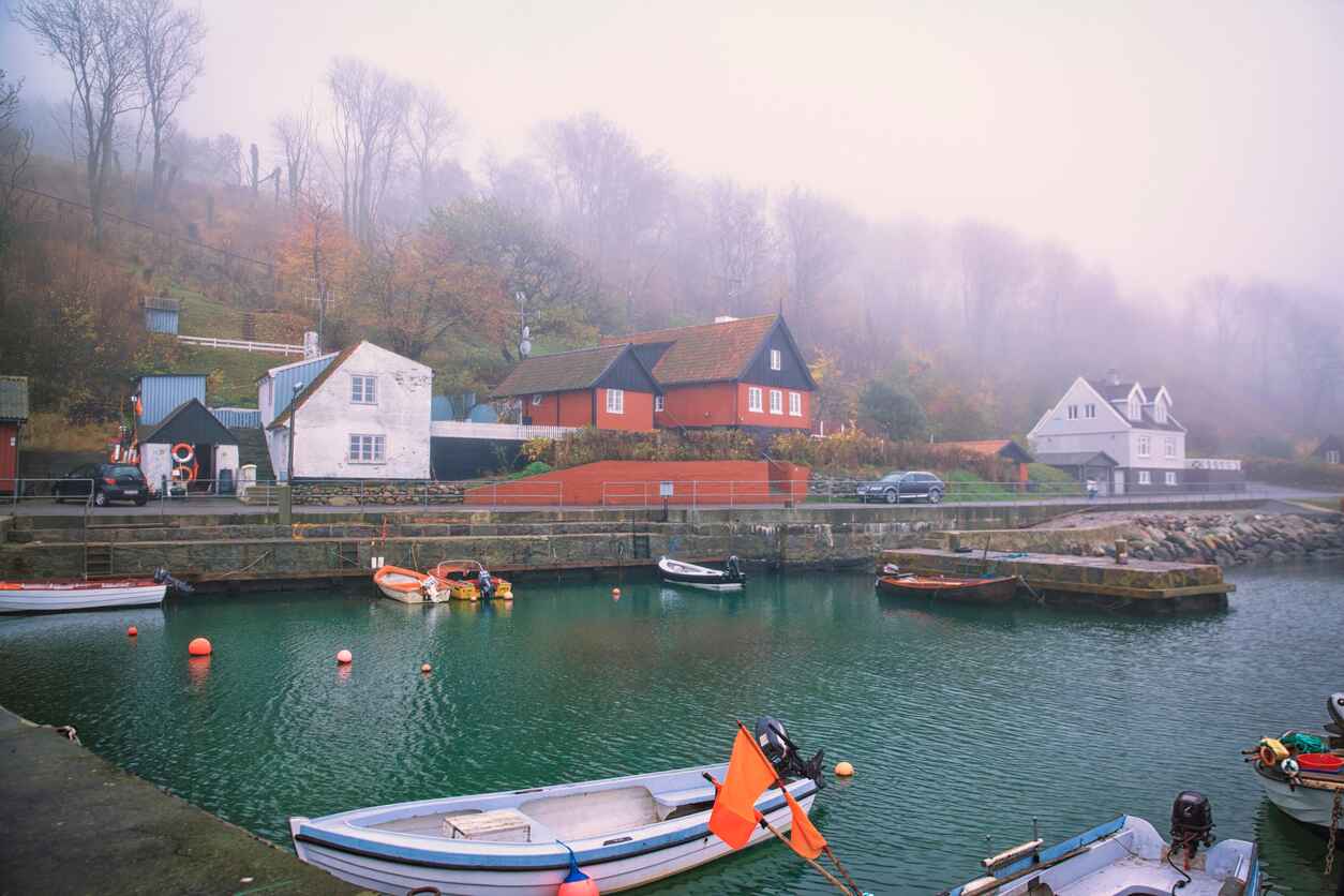 A tranquil Danish harbor with colorful houses, boats, and misty surroundings.
