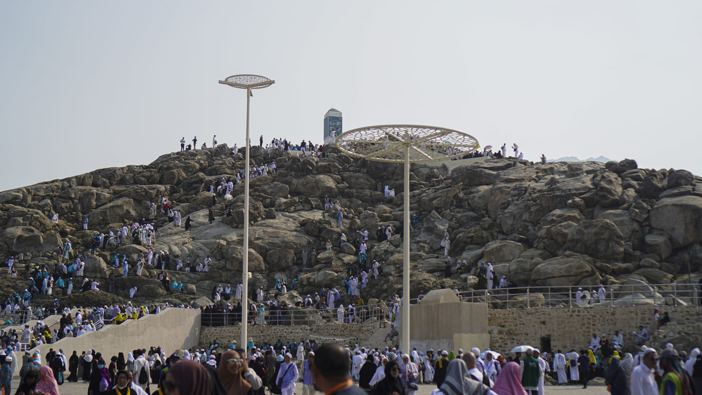 Crowds of pilgrims ascending the rocky slopes of Mount Arafat in Saudi Arabia, united in prayer on the sacred day of Arafat.
