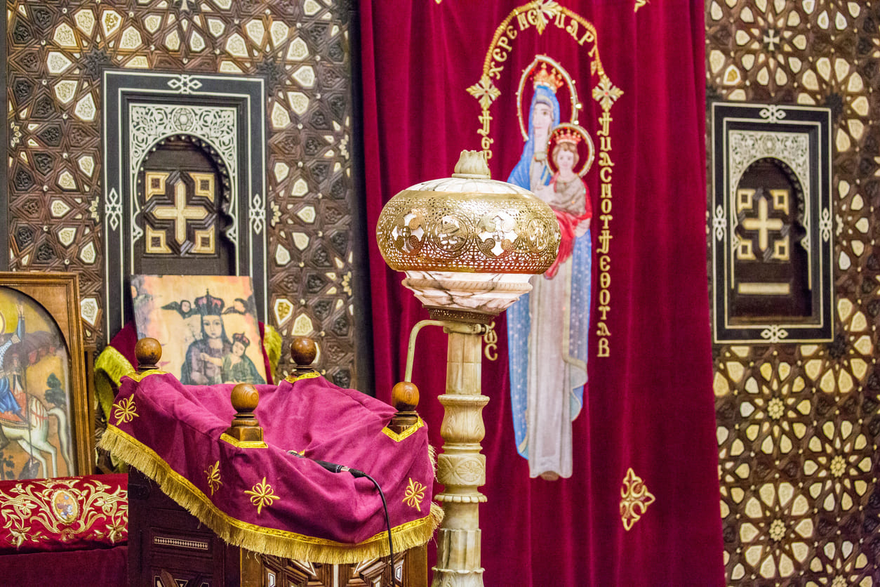 A richly decorated interior of Hanging Church (El Muallaqa) in Cairo, featuring icons, ornate woodwork, and a traditional Christmas setting.