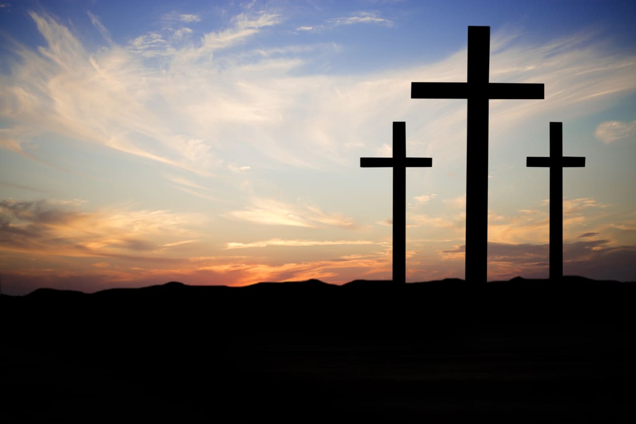A peaceful sunset frames three crosses in silhouette, representing the crucifixion scene remembered on Coptic Good Friday.