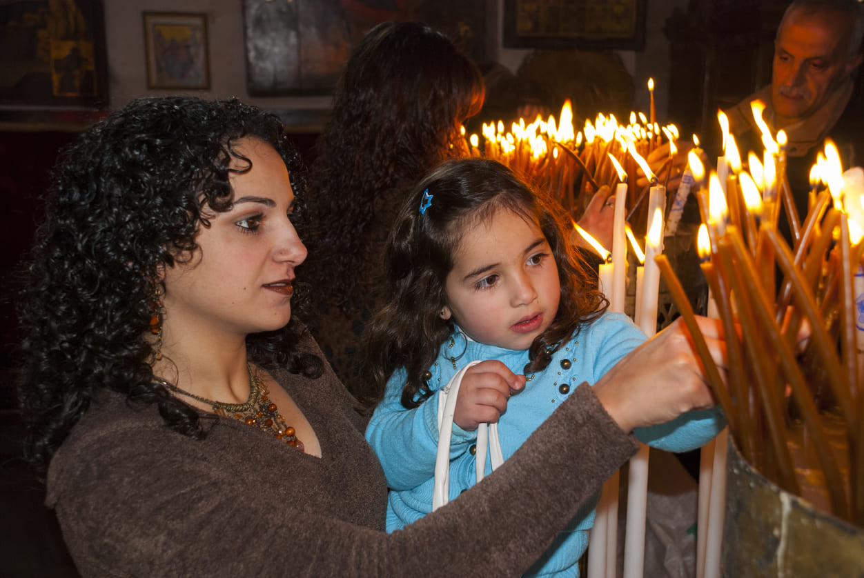 A peaceful moment as a mother and child light candles in church, capturing the quiet reverence of Coptic Holy Saturday.