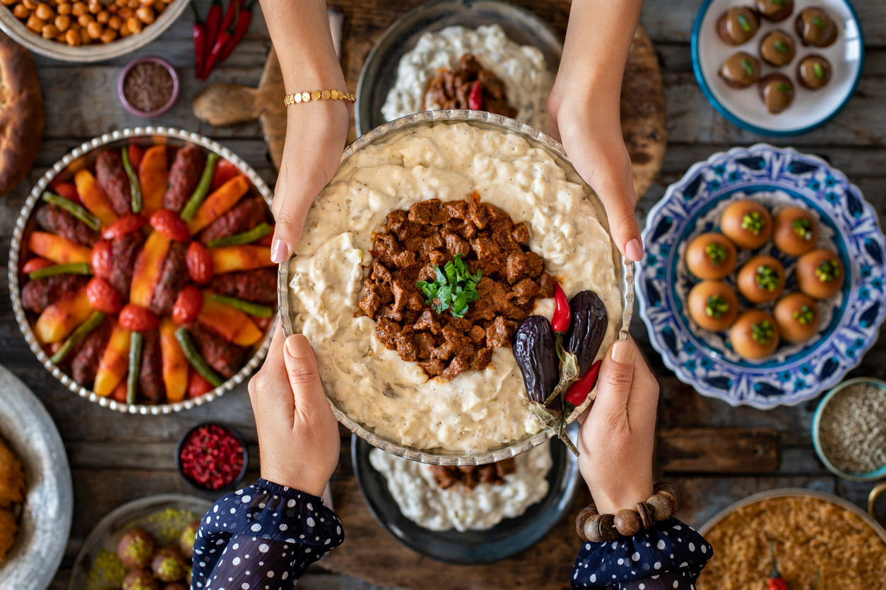 A colorful Eid el-Fitr meal featuring traditional dishes and sweets, shared warmly between hands over a festive table.
