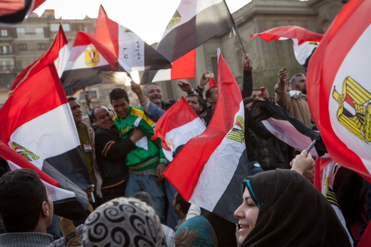 A vibrant crowd waves Egyptian flags in celebration and solidarity, capturing the powerful spirit of the January 25 Revolution.