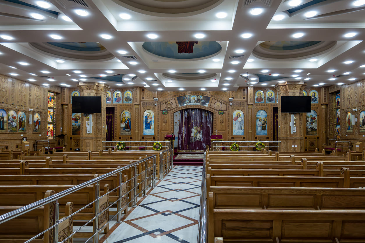 An elegant view of the richly decorated interior of Saint George Coptic Orthodox Church in Cairo, featuring intricate woodwork and sacred icons.