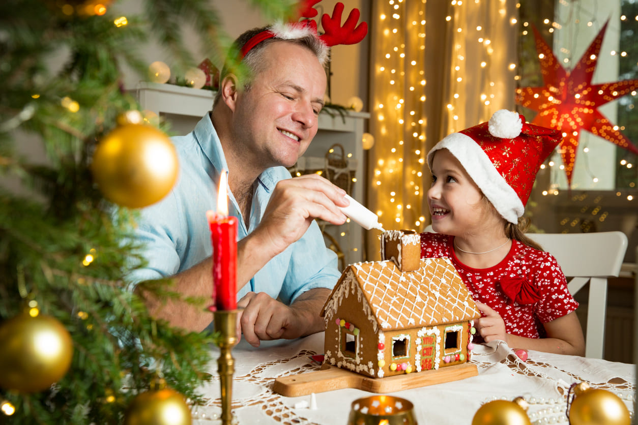 A warmly lit room where a father and daughter decorate a gingerbread house, capturing the joy and intimacy of Christmas Eve.