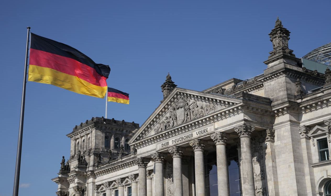 Reichstag building in Berlin with German flags flying, symbolizing Germany's democratic foundation.