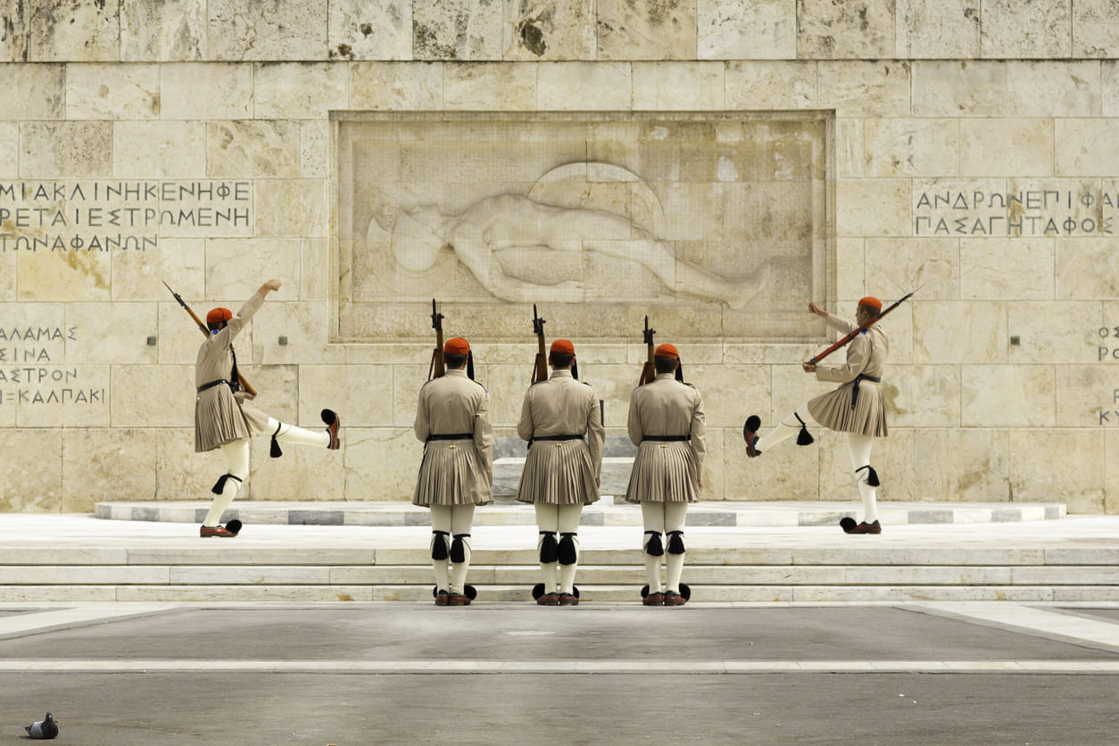 Evzones in traditional uniform perform a ceremonial guard change at the Tomb of the Unknown Soldier, symbolizing Greece's military honor and national remembrance.