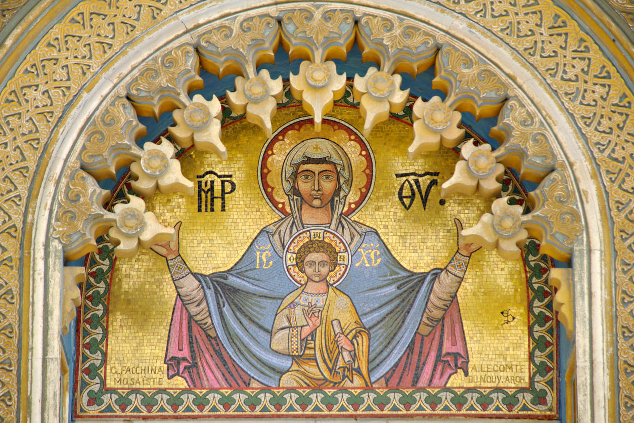 A detailed Byzantine mosaic depicts the Virgin Mary with the Christ Child, framed by golden tones and sacred Greek inscriptions.