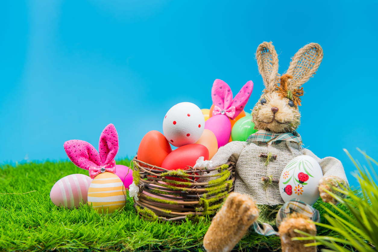 A cheerful arrangement of colorful Easter eggs and a bunny doll set on green grass, capturing the playful and festive side of Easter Sunday.