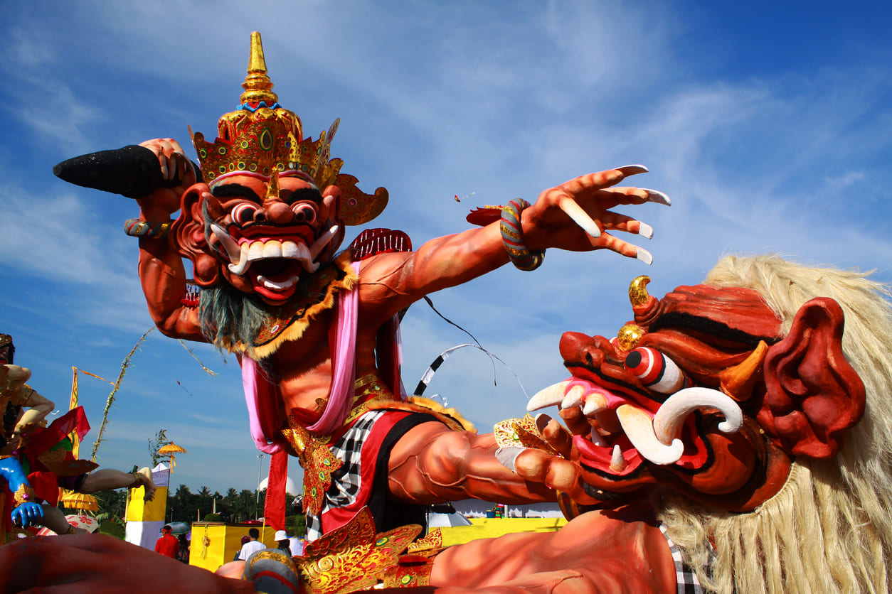 A colorful and intricately crafted Ogoh-Ogoh effigy towering against the blue sky, prepared for the traditional Nyepi eve parade in Bali.