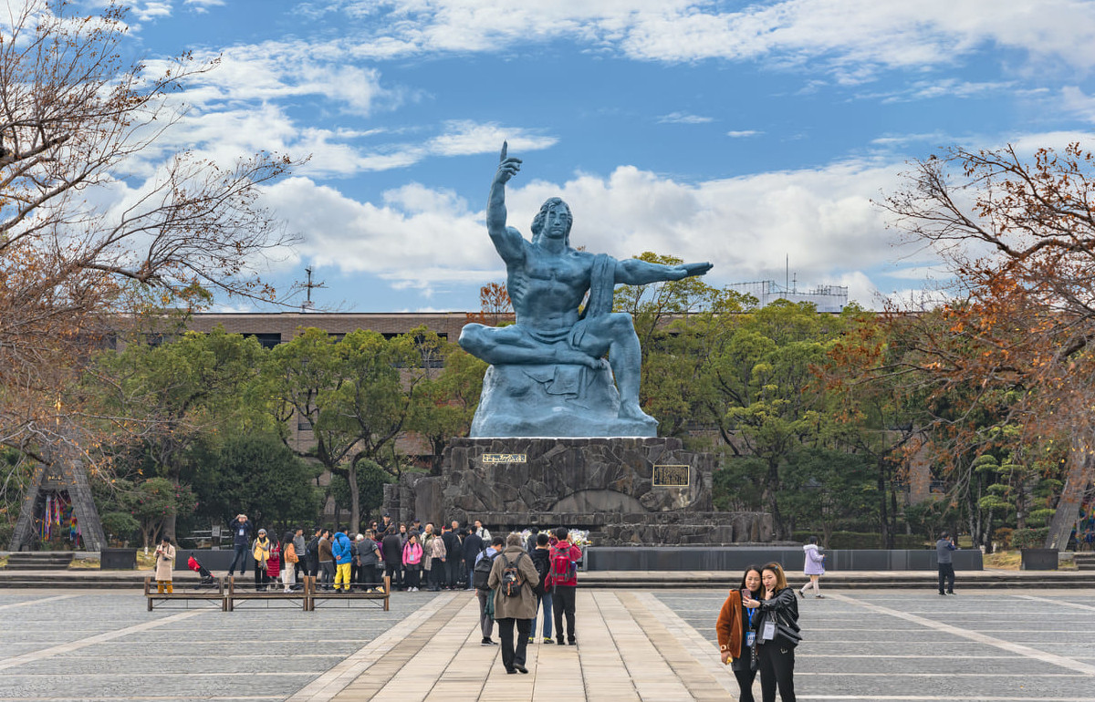 The towering Peace Statue at Nagasaki Peace Park, with visitors gathered below to honor the victims of the atomic bombing.