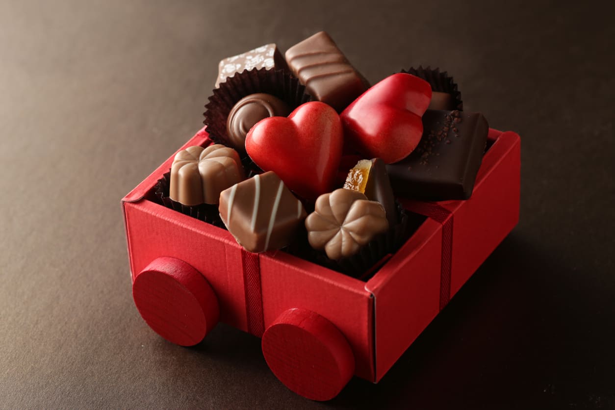 A red box neatly arranged with heart-shaped and assorted chocolates sits on a light surface, radiating warmth and charm.