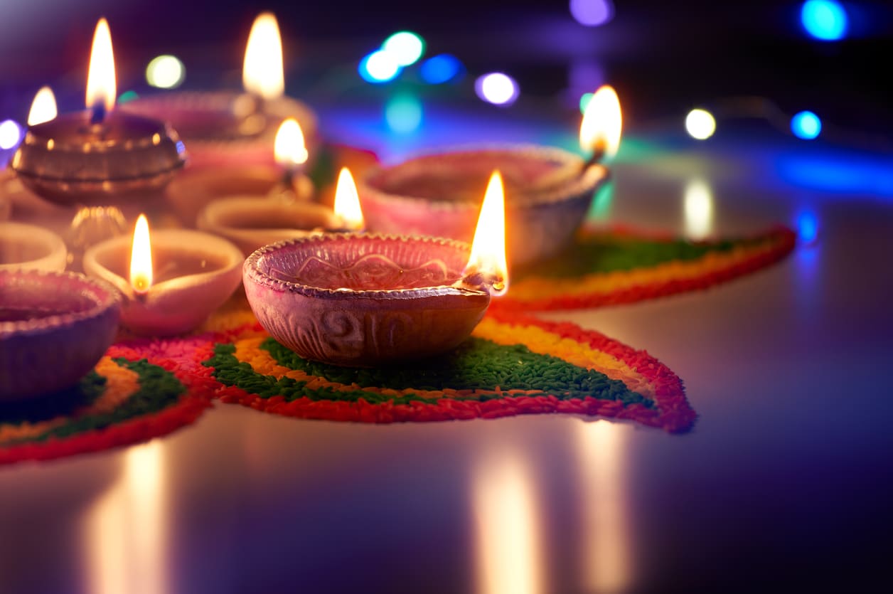 Beautifully lit clay oil lamps placed on a vibrant kolam design, reflecting the traditional charm of Deepavali celebrations.