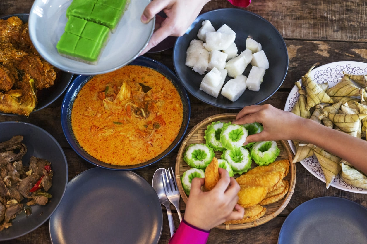 A vibrant Hari Raya Aidilfitri feast with ketupat, rendang, and kuih arranged beautifully, symbolizing festive joy and family togetherness.