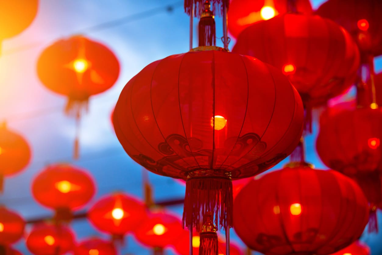 A close-up of vibrant red lanterns glowing against the evening sky, capturing the festive spirit of the Chinese Spring Festival in Mauritius.