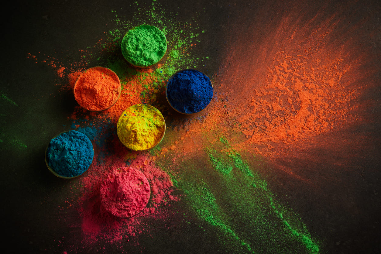 An array of bright colored powders scattered on a surface, capturing the vibrant essence of Holi celebrations.