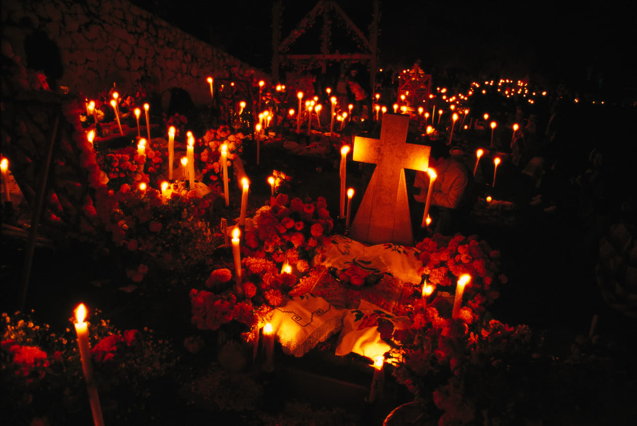 A candle-lit cemetery adorned with flowers and offerings, creating a peaceful tribute for All Saints' Day.