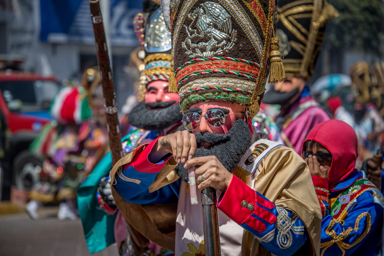 Participants in vibrant costumes and masks during a Cinco de Mayo parade in Puebla, celebrating Mexico's victory in the Battle of Puebla.