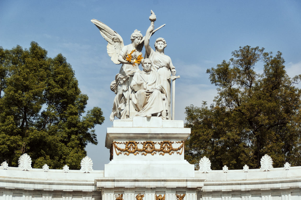 The monument to Benito Juárez, a grand white marble monument in Mexico City surrounded by trees and blue sky, symbolizing his lasting legacy.