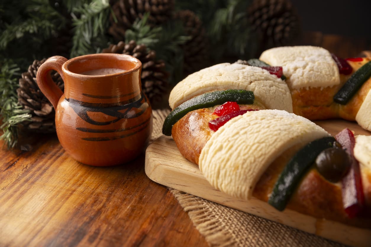 A festive setting with a traditional Rosca de Reyes and a clay mug of hot chocolate, capturing the warmth of the Day of the Holy Kings celebration.