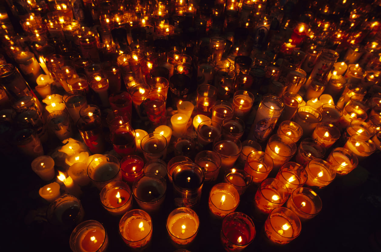 Rows of lit candles glowing in the dark, creating a solemn and peaceful setting for the Easter Vigil on Holy Saturday.
