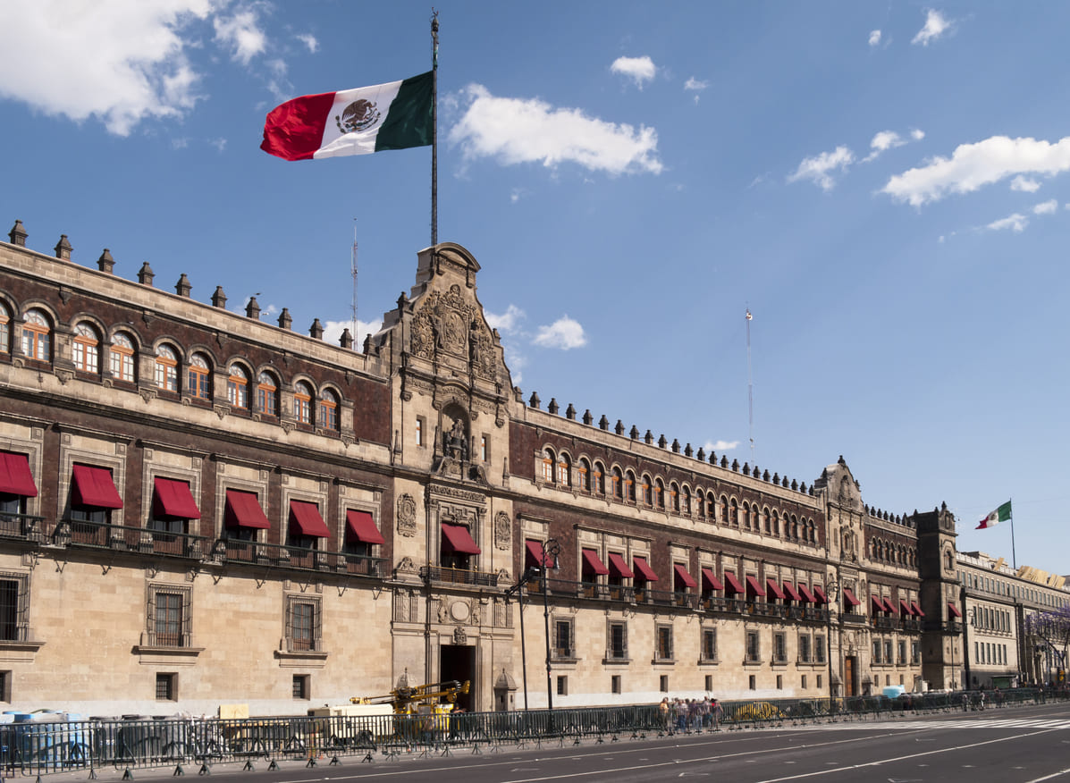 The National Palace in Mexico City with the Mexican flag waving above, symbolizing government authority and national pride.