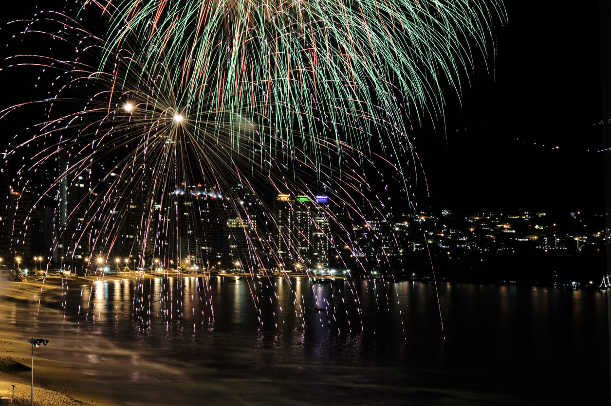 A stunning display of fireworks over the beach and cityscape of Acapulco, Mexico, celebrating the arrival of New Year's Day.