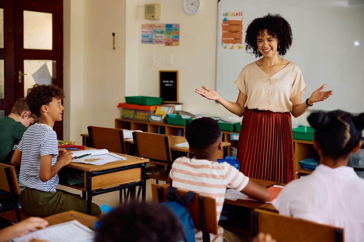 A smiling teacher interacting with her students in a lively classroom, capturing the essence of Teacher's Day.