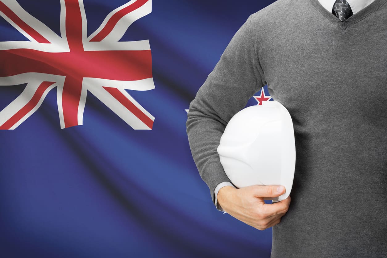 Worker holding a safety helmet against the backdrop of the New Zealand flag, representing respect for workers and the significance of Labour Day.