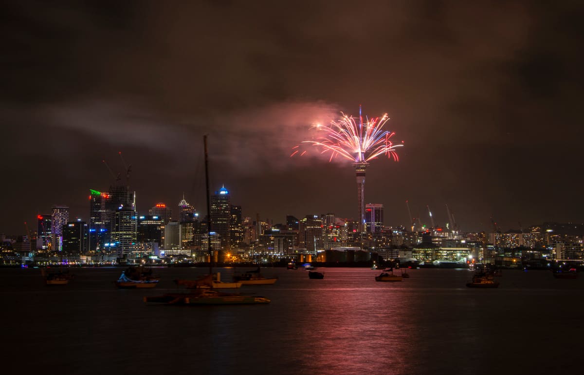 A dazzling burst of fireworks illuminates Auckland's Sky Tower and city skyline, capturing the festive spirit of New Year's Day in New Zealand.