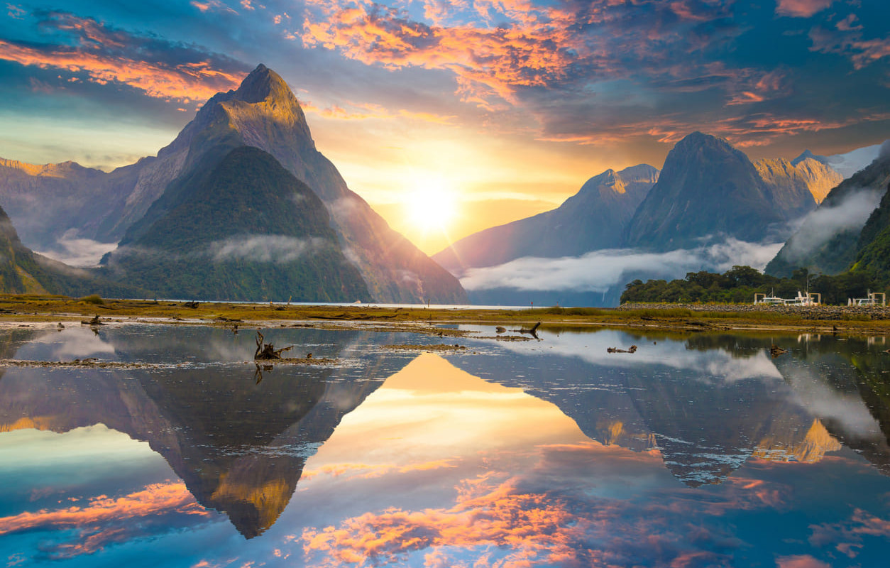 A breathtaking sunrise over Fiordland National Park, showcasing the dramatic landscapes that inspire pride on Southland Anniversary Day.