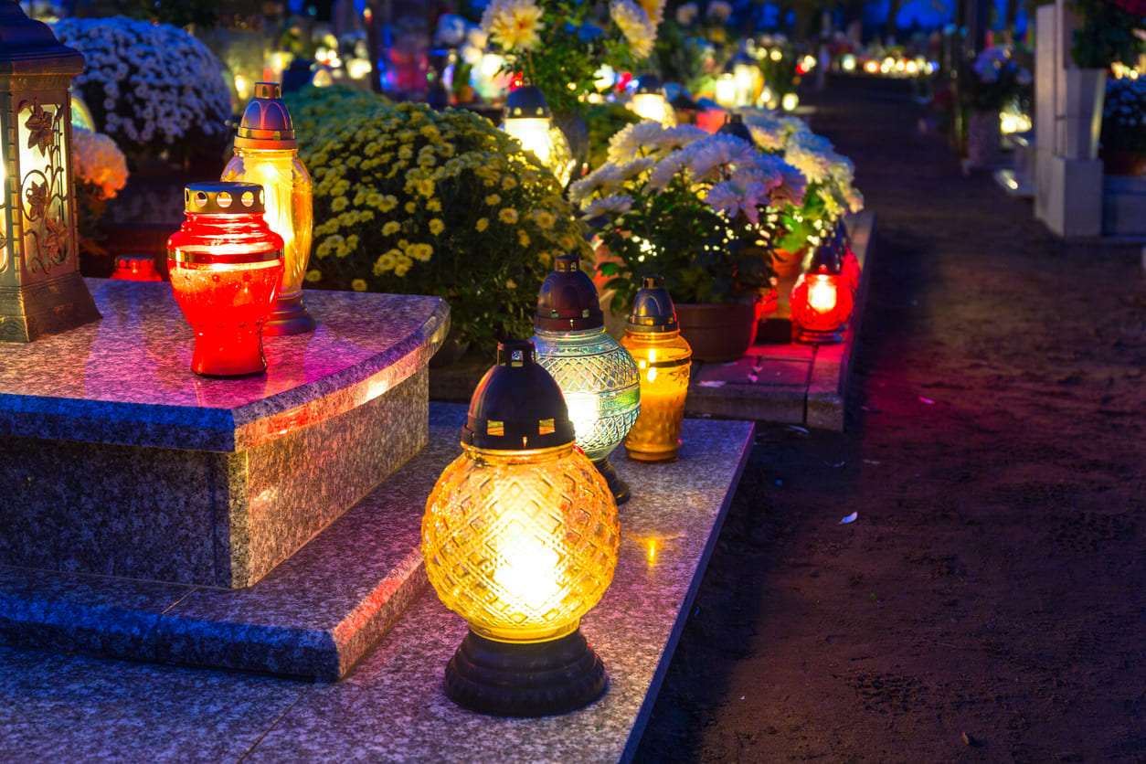 Bright candles and vibrant flowers adorn a cemetery pathway, creating a warm and solemn tribute during All Saints' Day.