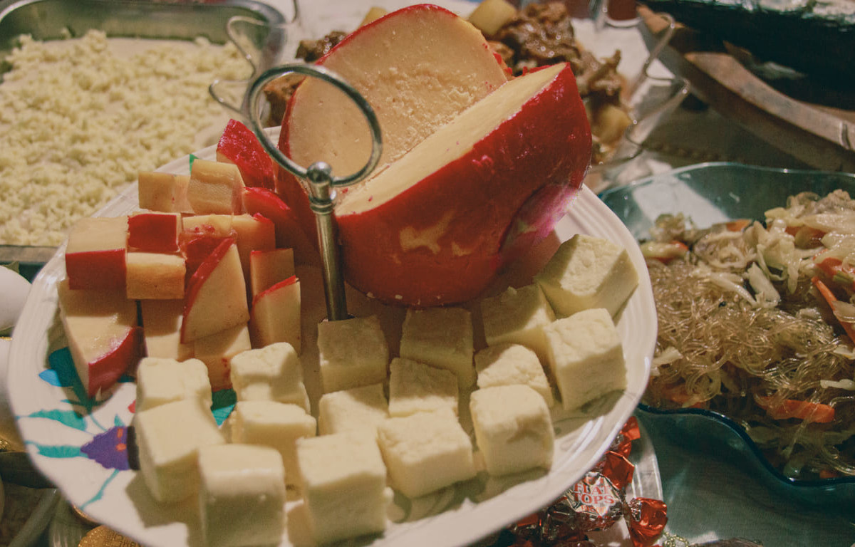 A traditional Noche Buena table with queso de bola, pancit, and other festive dishes enjoyed during Christmas Eve in the Philippines.
