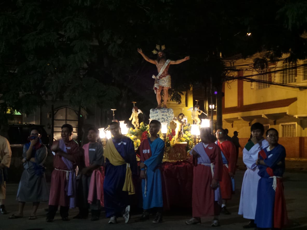 Devotees dressed in colorful robes gather around a statue of the risen Christ during a joyful Salubong procession at San Agustin Church in Manila.