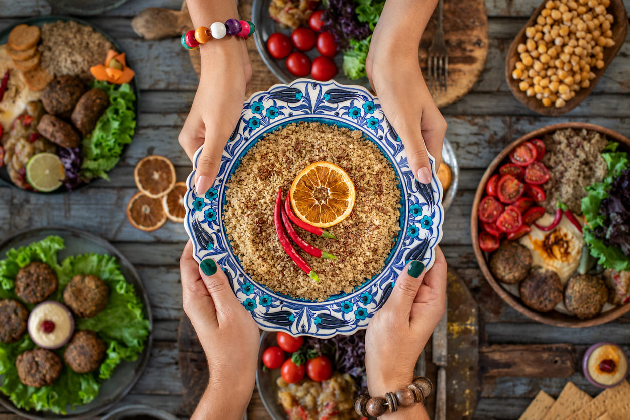 A beautifully decorated dish is shared among friends, surrounded by vibrant plates of traditional festive food.
