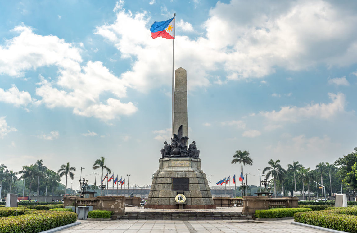 The Rizal Monument in Manila with the Philippine flag proudly waving, symbolizing the nation's enduring spirit and patriotism on Independence Day.