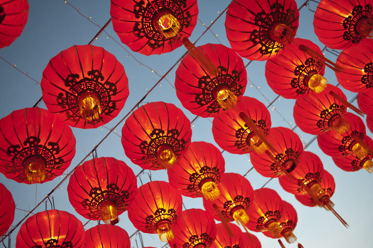 Rows of traditional red Chinese lanterns hanging against a clear sky, glowing warmly to mark the festive spirit of Chinese New Year.