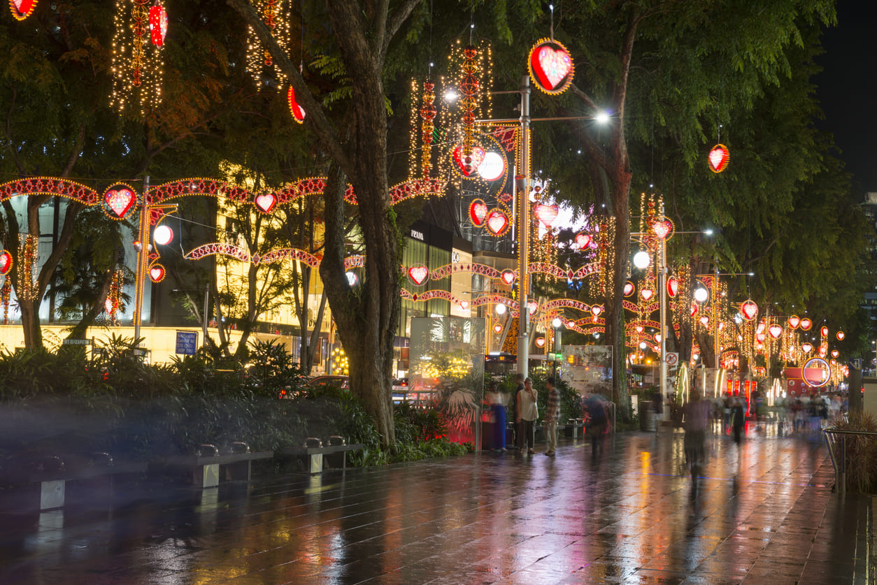 Orchard Road beautifully lit with heart-shaped lights and colorful decorations, capturing the festive spirit of Christmas Eve in Singapore.