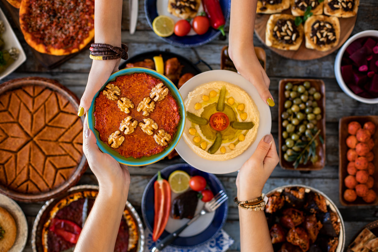 A colorful and inviting table filled with traditional dishes, with hands exchanging plates, symbolizing the warmth, generosity, and communal spirit of Hari Raya Puasa.