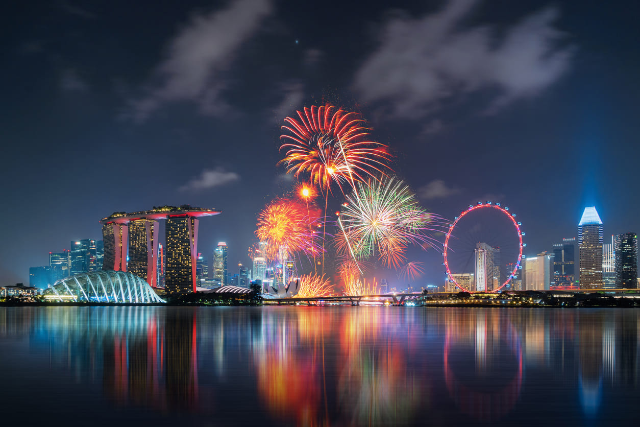 Vibrant fireworks illuminating the night sky over Marina Bay, with iconic Singapore landmarks glowing in celebration of National Day.