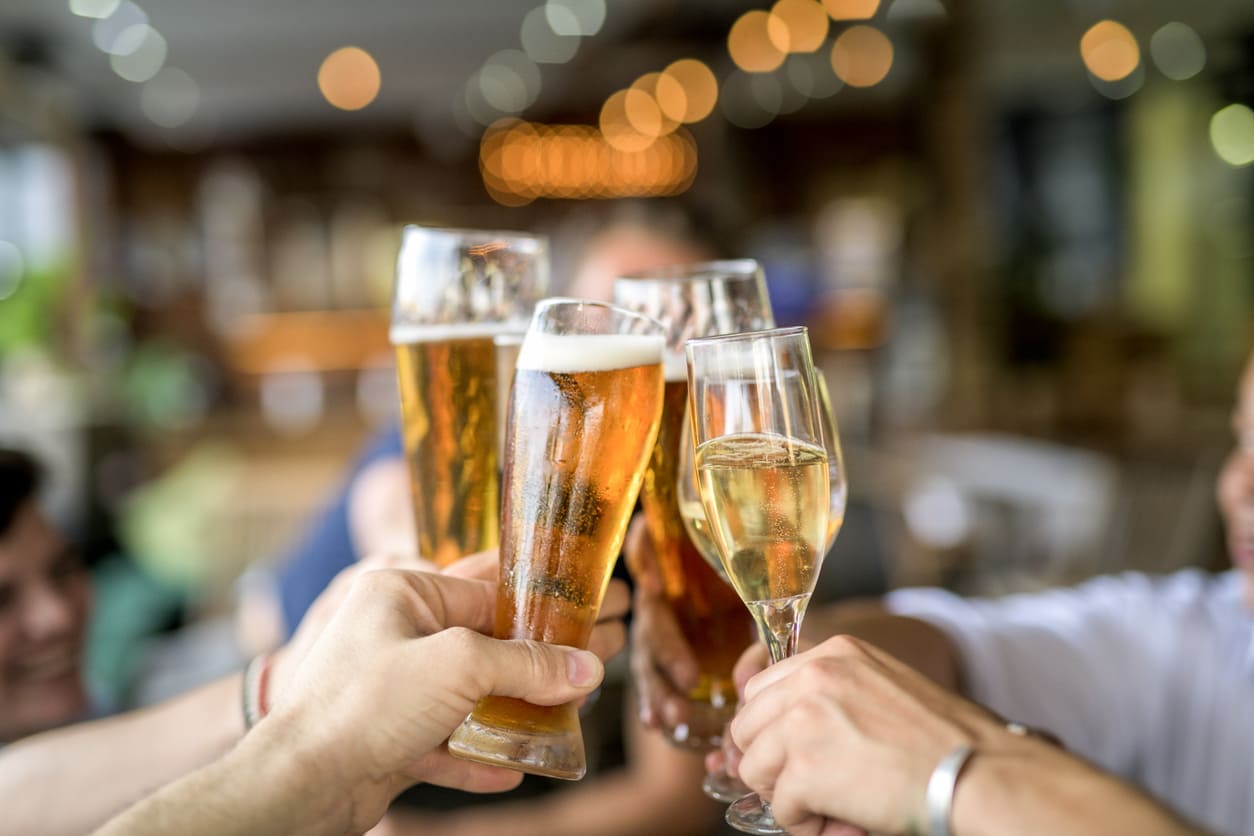 A close-up of friends clinking glasses filled with beer and champagne, celebrating together in a lively and festive setting.