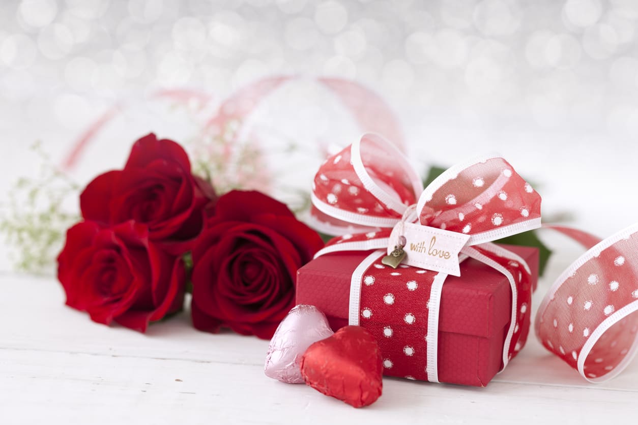 Red roses, heart-shaped chocolates, and a ribbon-wrapped gift box, symbolizing love and affection on Valentine's Day.