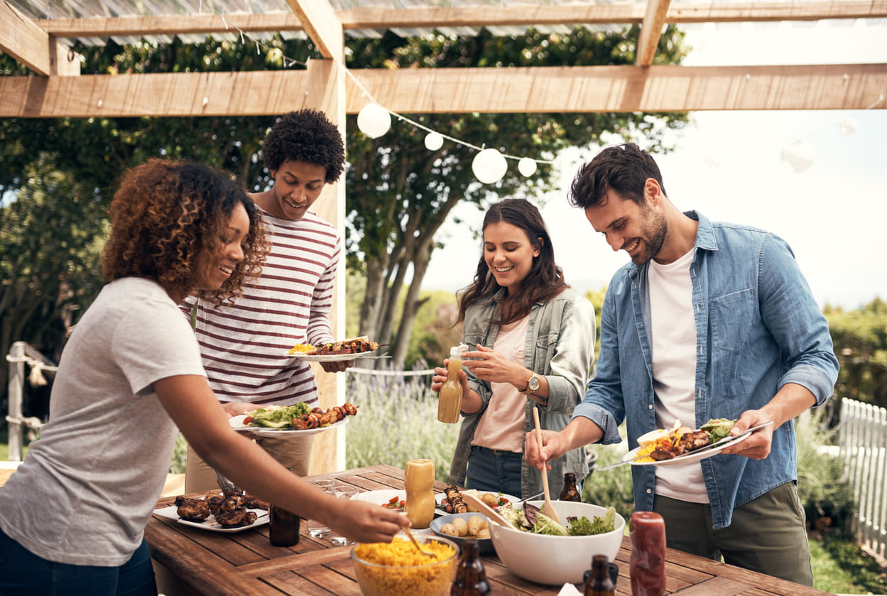 A group of people gathered around an outdoor table, smiling and serving food, capturing the joyful spirit of Family Day in South Africa.