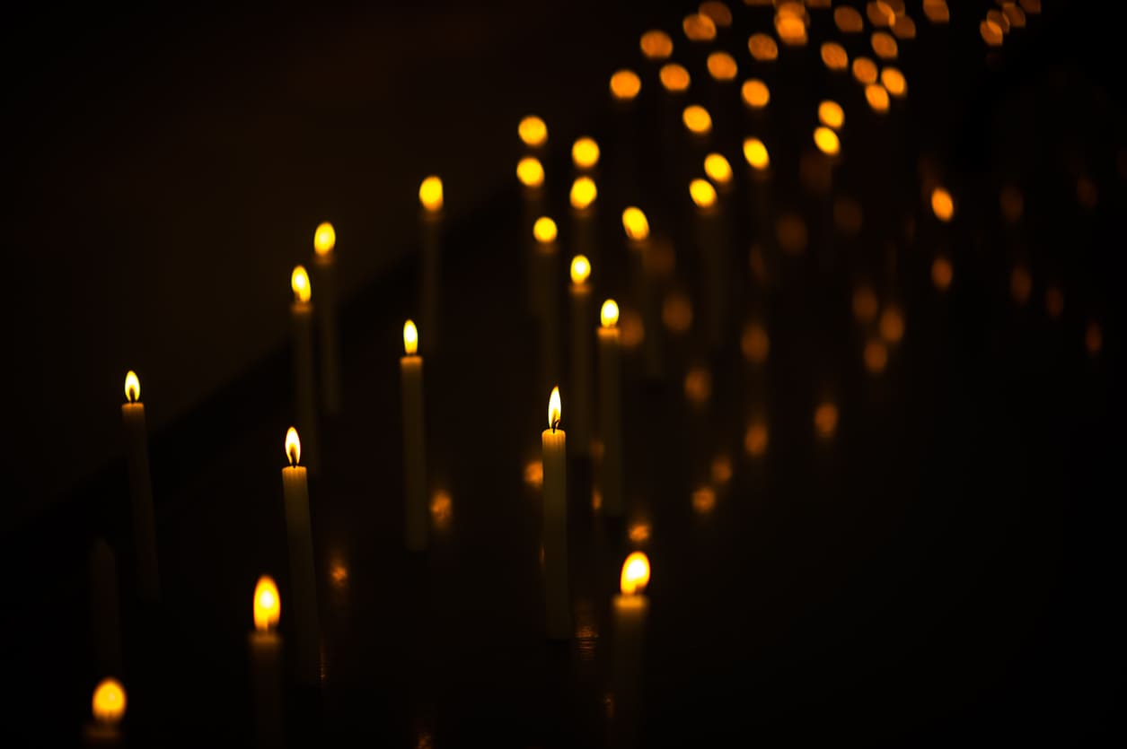 Rows of softly glowing candles illuminate the darkness, creating a serene and reflective atmosphere.