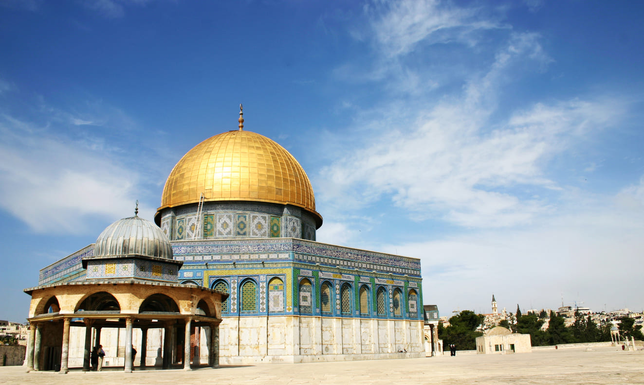 A stunning view of the Dome of the Rock in Jerusalem, with its iconic golden dome under a bright blue sky.