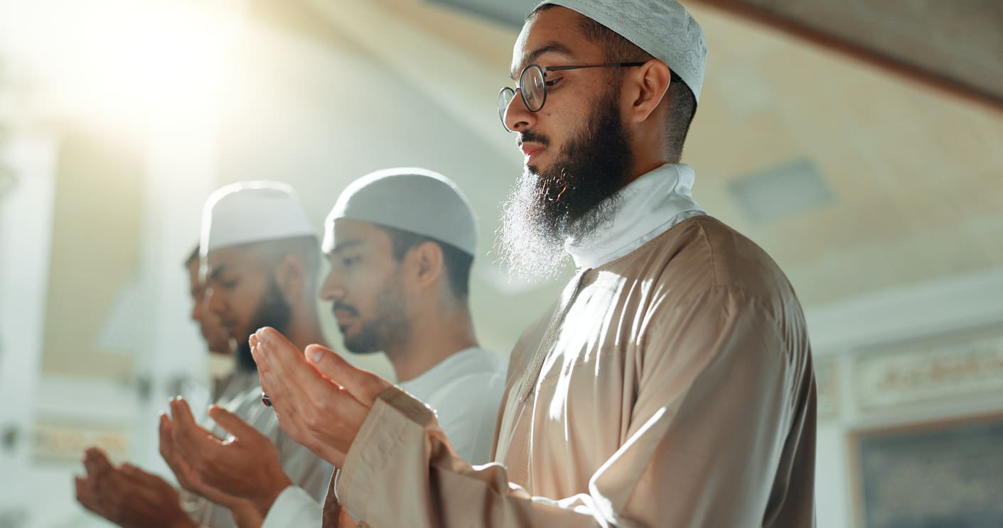A group of Muslim men seated in prayer, deeply engaged in worship during a peaceful night in Ramadan.